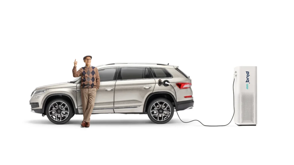 An elderly man wearing glasses and a sweater vest leans against a silver SUV plugged into an electric charging station with the brand name bp on it, set against a plain white background.