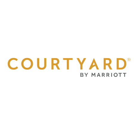 Courtyard by Marriott logo with COURTYARD in large gold letters and BY MARRIOTT in smaller gray letters underneath on a transparent background, highlighting free EV loading stations for guests using Pluq.